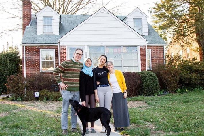 Family standing outside a house with a guest student smiling for the picture | Host Family Stay