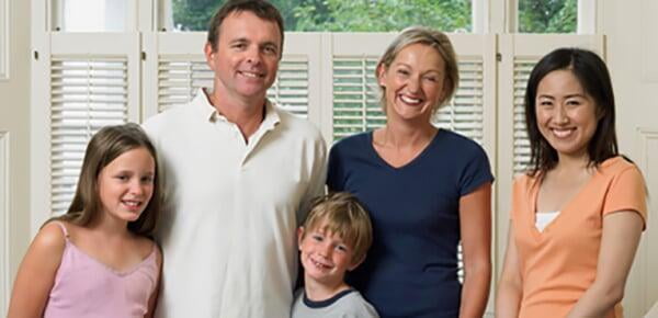 Host family standing with their guest student in front of a window looking super happy | Host Family Stay